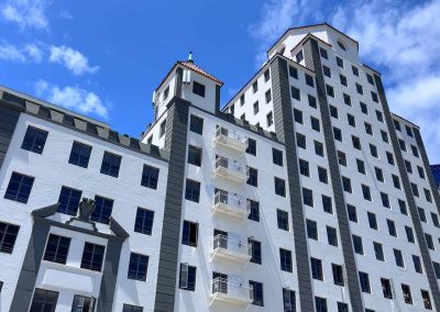 Modern high-rise buildings with white facades and castle-style roofs under a clear blue sky.